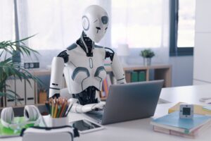 AI humanoid sitting at a desk with an open laptop, symbolizing conversational automation in business.